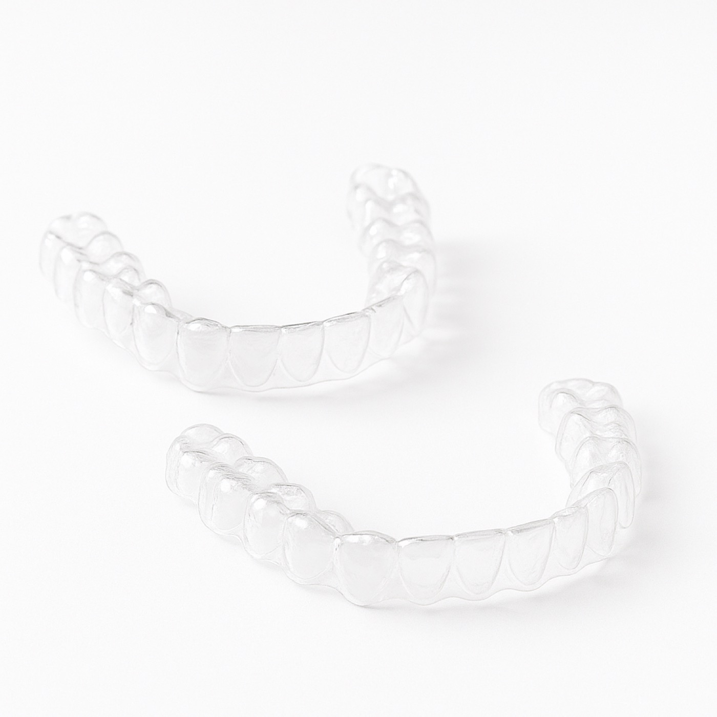 Woman smiling confidently while holding Invisalign clear aligner tray